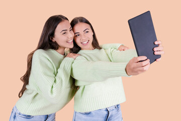 two female twin sisters, hispanic, make selfie photo with tablet