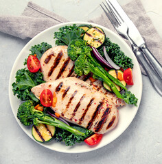 Grilled chicken with vegetables on light background.