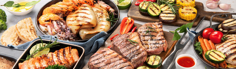 Grilled fish, seafood and meat assortment on light background.