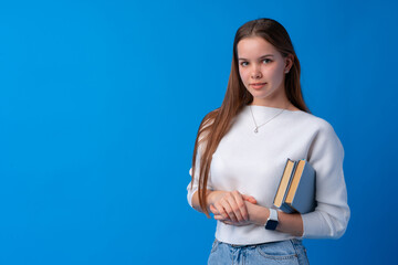 Smiling woman holding books against blue background