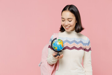 Smiling teen student girl of Asian ethnicity wear sweater backpack hold books hold in hands Earth world globe isolated on pastel plain light pink background Education in university college concept
