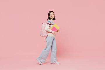 Full body side view teen fun student girl of Asian ethnicity wearing sweater hold backpack books walk going look aside isolated on pastel plain pink background Education in university college concept. - obrazy, fototapety, plakaty