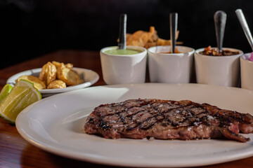 Cooked steak next to mexican salsas