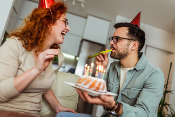Family couple in party hats celebrating birthday at home