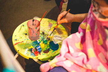 An little artist is dipping a paint brush into a watercolor palette. Little Artist with palette and...