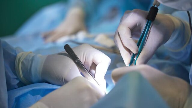 Diverse tools for operational intervention in doctor&rsquo;s hands. Surgeons using forceps in their work. Close up. Blurred backdrop.