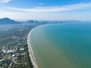 flying above the clean ocean and curve of  town with mountain