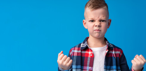 Portrait of angry little boy on blue background