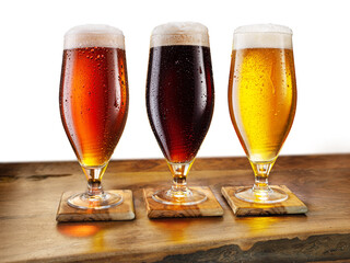 Cooled glasses of three different beer with condensate drops on the wooden table. File contains clipping path.