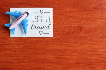Top view image of toy plane and blue paper with text LET'S GO TRAVEL. Copy space for text