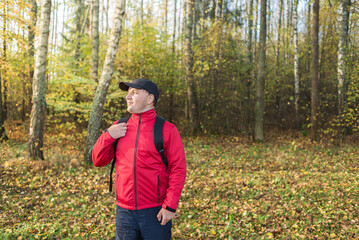 Young man with backpack in the forest. Young man in a red jacket with a backpack in the forest