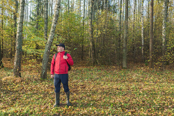 Fototapeta premium Young man with a backpack walks through the forest. Travel theme. Young man with a backpack walks through the forest
