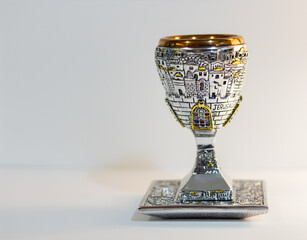 Traditional, decorative Jewish kiddush cup. Silver cup with saucer filled on a blurred background