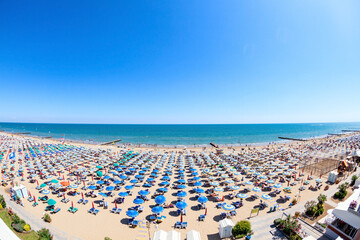 Aerial view on the Lido di Jesolo beach full of umbrellas and tourists swimming in the Adriatic...