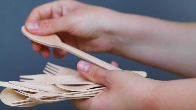 Wooden disposable cutlery in women's hands. Forks, spoons and knives.The topic of environmental protection.Disposable ecological tableware for kitchen and restaurant.