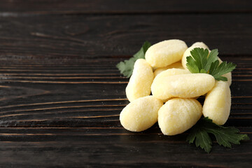 Raw potato gnocchi with parsley on wooden background