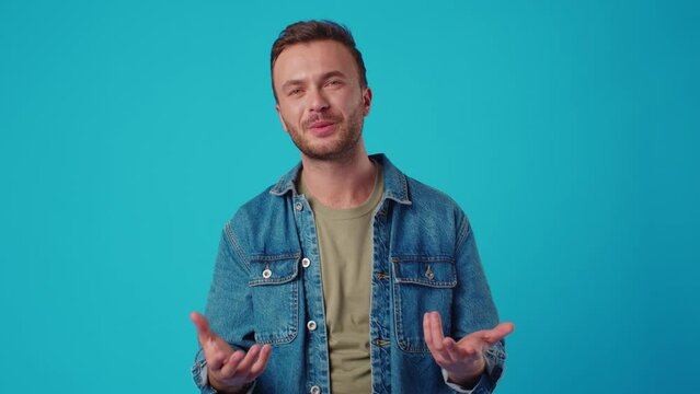 Young caucasian man standing and talking to camera on blue background