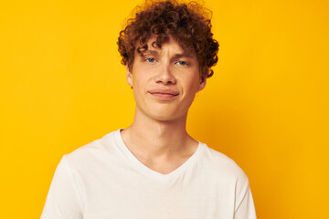 curly red-haired guy in a white t-shirt on a yellow background