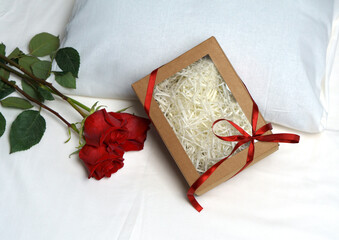 Three red roses, a heart and a box with a gift on the background of the bed.
