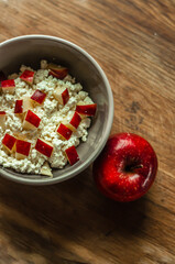 delicious and healthy breakfast homemade cottage cheese curd in a ceramic plate with red apple on wooden background, healthy food, dairy farm products, milk products