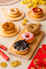 assorted donuts or doughnut plate on wood tray and shoot in cream background and chinese ornament