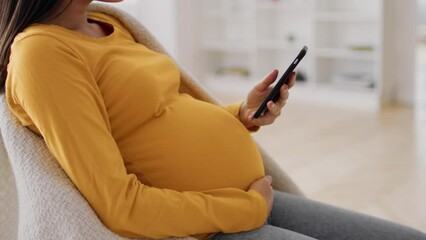 Pregnancy App. Young pregnant woman relaxing with smartphone at home - Powered by Adobe