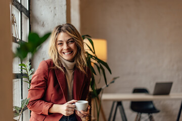 Portrait of smiling businesswoman, looking directly at the camera, holding a cup of tea.