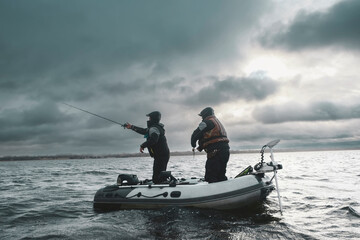 Anglers catch fish from a boat with a spinning rod.