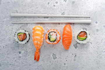 A set of sushi nigiri and rolls with salmon and chopsticks on a stone background. Japanese dish...
