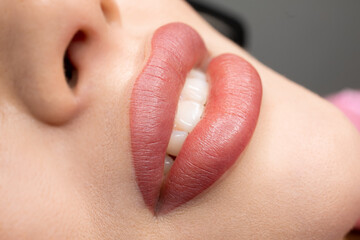 permanent lip makeup completes the lip makeup procedure with a close-up - obrazy, fototapety, plakaty