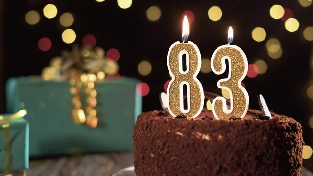 Birthday candle number eighty three on a sweet cake on the table, 83rd birthday. Fire from the lighter, blow out the holiday candle.