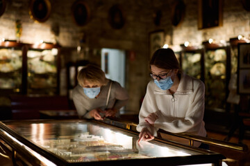 Attentive tween girl with senior woman exploring art museum