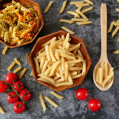 Various types of pasta (fusilli, penne, cavatapi, cannelloni, spaghetti) on black background, Raw pasta set and tomato, set, collection