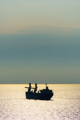silhouettes of ship at sea, dramatic seascape with sunset sky, bright sunlight reflected from the waves