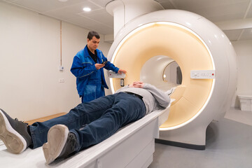 one engineer of mri apparatus lies in scanner and adjusts it, other outside. 