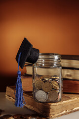 Jar with coins and graduation hat on a book, scholarship and savings concept