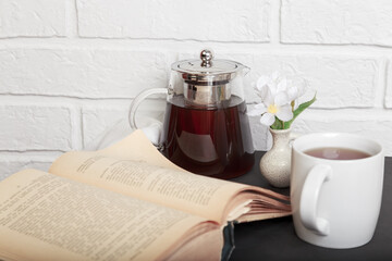 Morning tea. An open old book on the kitchen table and a cup of tea. Leisure reading in a cozy loft-style room