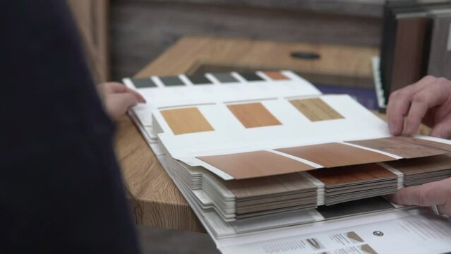 Customer choosing design for house interior, decoration. New Apartment renovation. Furniture surface shopping catalog looking, wood, stone texture sample tiles. Furniture store. Flat repair. 