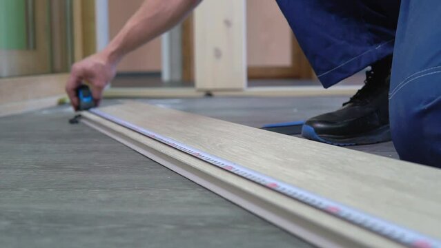 Tape measure rolling tool in hands of professional worker man. Tape line instrument using, building and repair equipment. Construction, projecting, planning indoors, male job. DIY building close up.