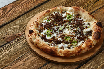 Delicious homemade pizza with mozzarella, mushrooms, beef and chicken. Wooden background, selective focus.