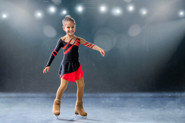 Little skater rides on rings in red and black dress on ice arena