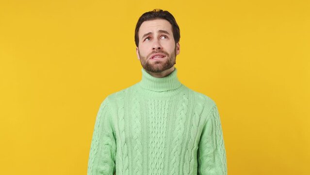 Confused puzzled upset young brunet bearded man 20s years old wears mint shirt look camera spreading hands say oops isolated plain yellow background studio portrait. People emotions lifestyle concept
