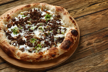 Delicious homemade pizza with mozzarella, mushrooms, beef and chicken. Wooden background, selective focus.