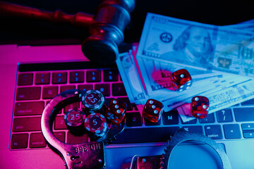 Handcuffs, gavel and dice on a laptop. Online casino concept