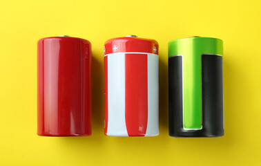 New D batteries on yellow background, flat lay
