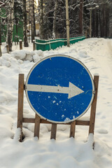 Road sign with an arrow next to the road close-up. Winter. Outdoors. Selective focus