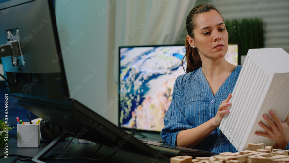 Poster woman architect holding maquette and using computer with touch screen for architectural development.