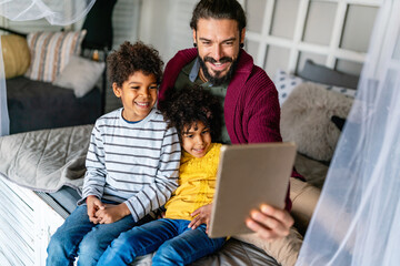 Multiethnic family happiness concept. Happy father and children using tablet and having fun at home