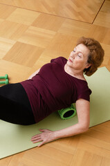 Senior woman exercising with sport foam roller at home. Healthy lifestyle, active elderly.