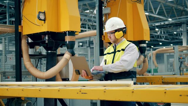 Factory worker with a laptop is observing a moving fiberglass item